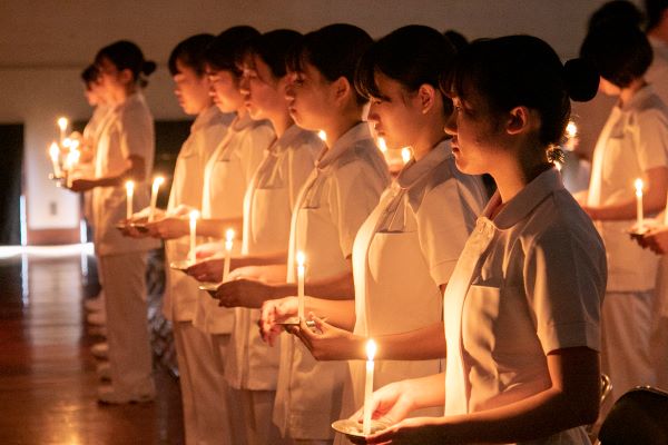 看護学生がろうそくを持ち並んでいるところ