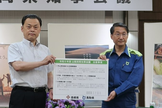 合意事項を記載したパネルを掲げる平井鳥取県知事と丸山島根県知事