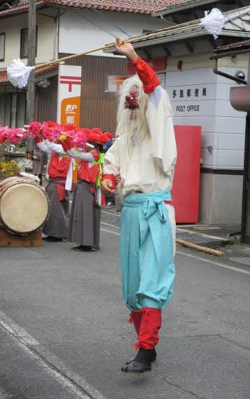 猿田彦は赤い天狗面をかぶり、棒を持って踊る