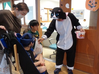 化け猫の仮装をした職員とお菓子を受け取る子どもら