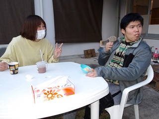 メロンパンを頬張る児童と笑顔の職員