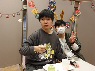 ケーキを頬張る児童とピースをする職員