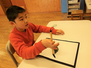 筆を持って手本を見ている児童