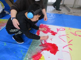 模造紙に絵具を広げる児童