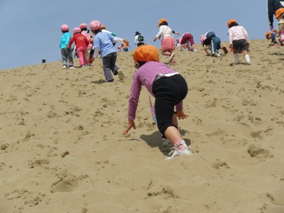 子どもたちが砂丘をかけあがる写真