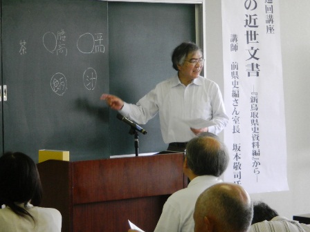 黒板に板書しながら解説を行う前県史編さん室長坂本敬司氏の写真
